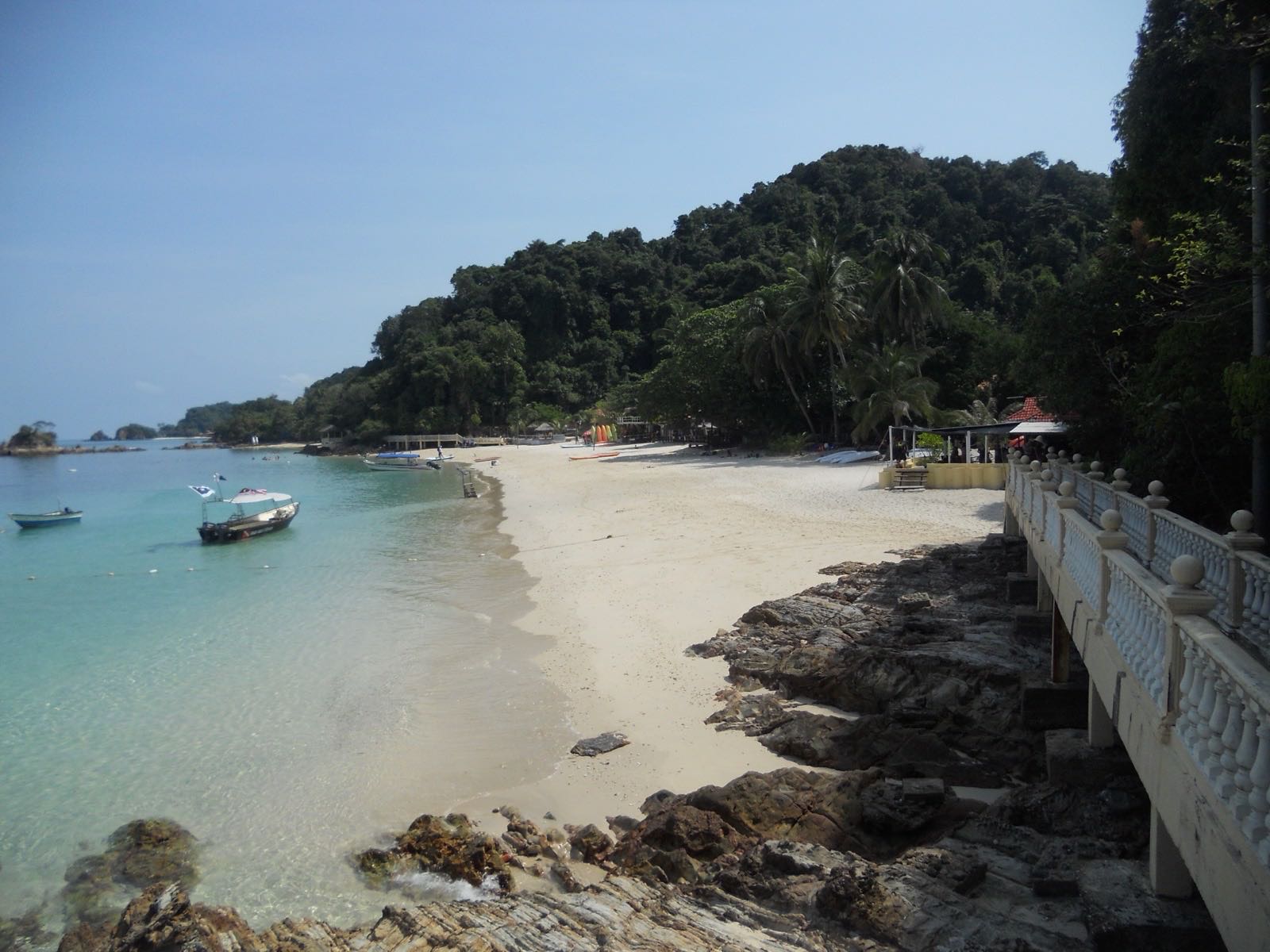 Sheltered white-sand cove with clear shallow water and moored boats on Pulau Kapas, Terengganu.