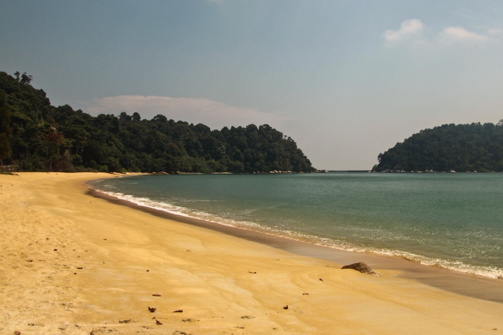 Empty golden-sand bay framed by wooded headlands on Pulau Pangkor, Perak.