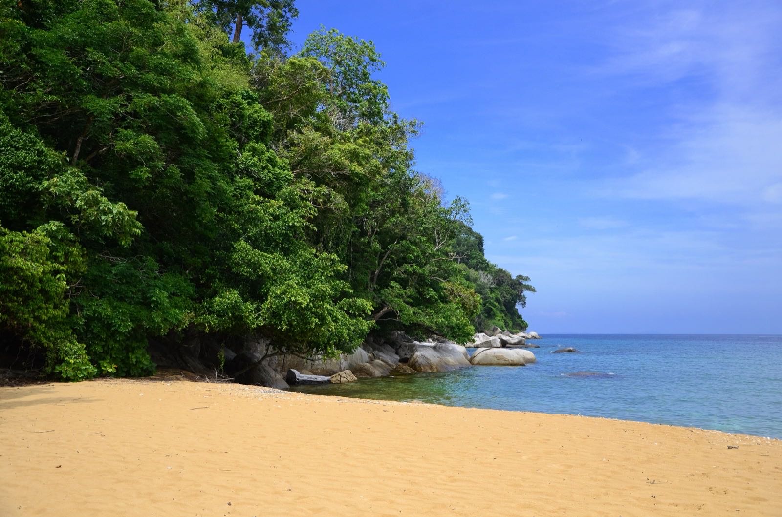 Deserted golden beach beside lush rainforest and granite boulders on Pulau Tioman.