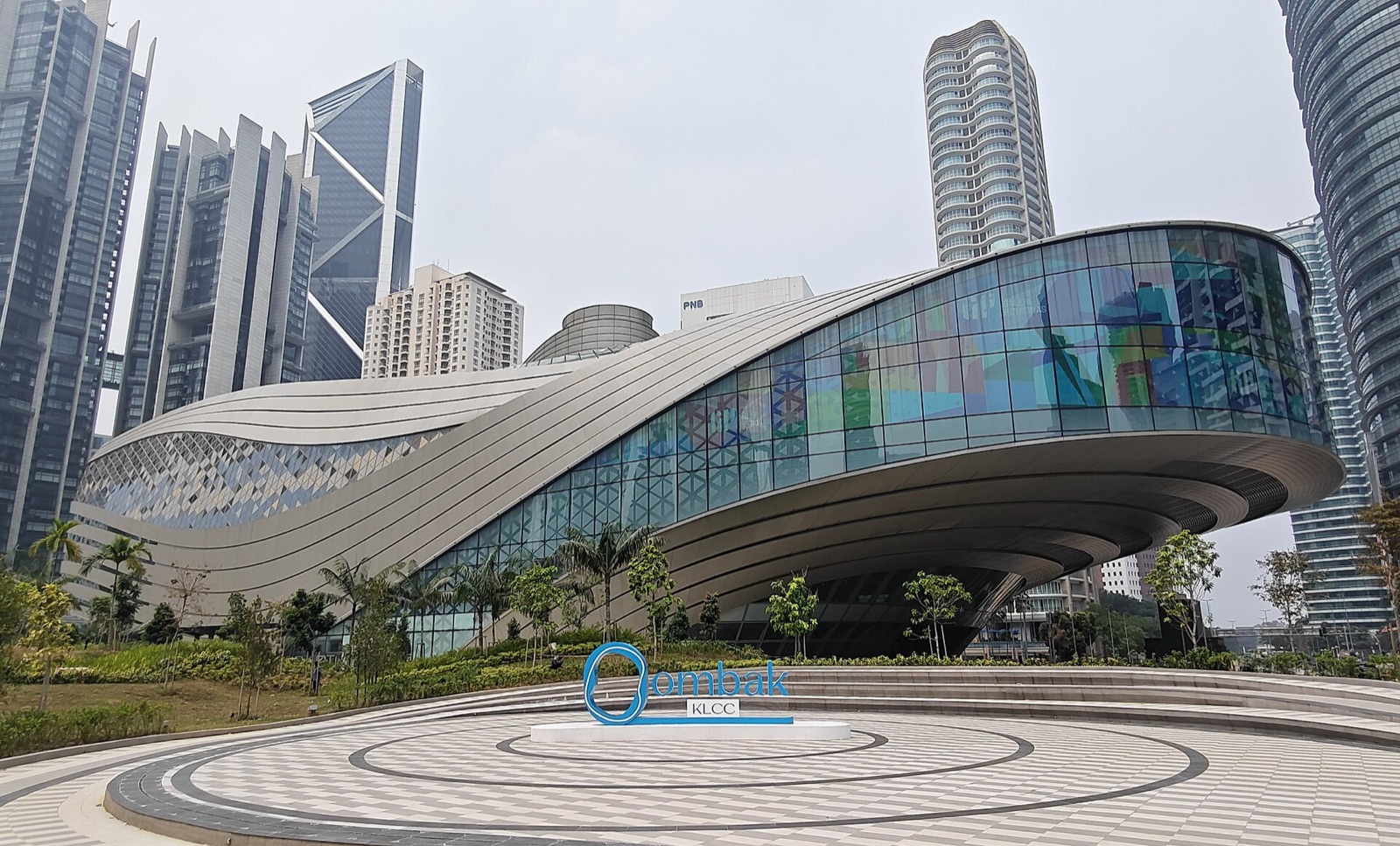 The wave-shaped Ombak KLCC building seen from its forecourt, with the KLCC towers behind.